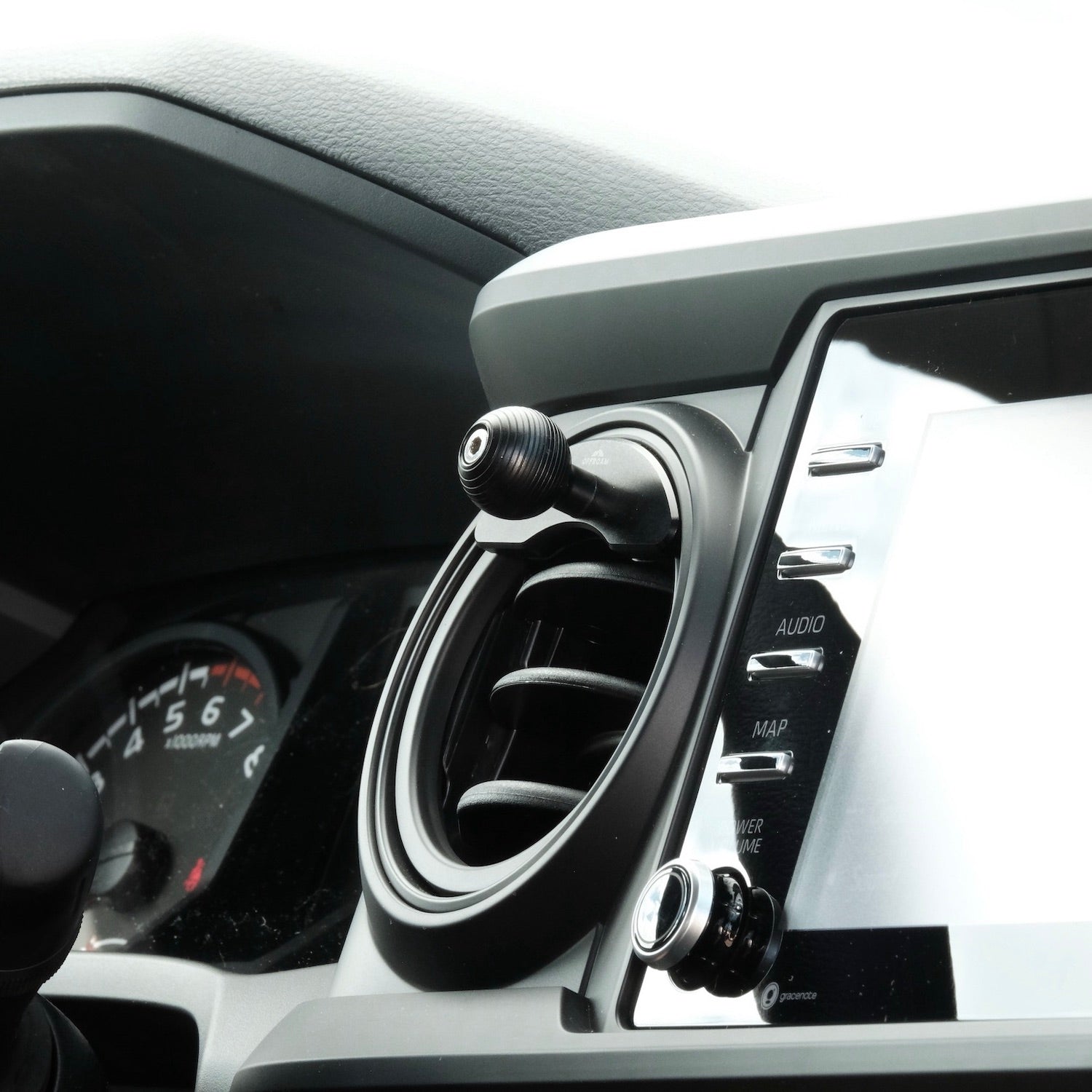 Image of Offroam Mounting Base installed securely in Toyota Tacoma 2016-2023 | Tundra 2014-2021. This premium all metal phone mounting base installs easily without drilling or glue. Perfect placement without blocking screens, driver view, or air flow.