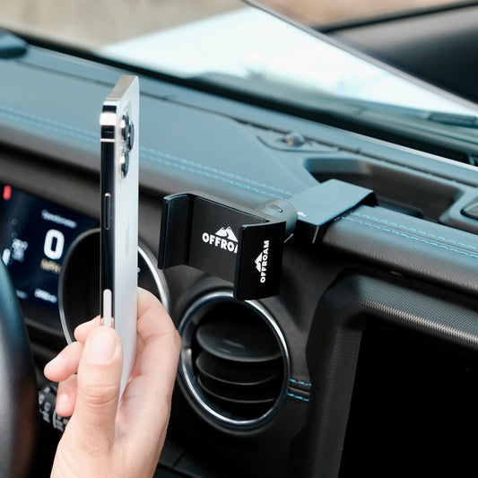 Image of Offroam Phone Mount installed securely in Jeep Wrangler 2018-2023 | Gladiator 2019-2023. This premium phone mount installs easily without drilling or glue. Spring loaded Universal holder for use with any phone. Perfect placement without blocking screens, driver view, or air flow. Fully adjustable positioning.