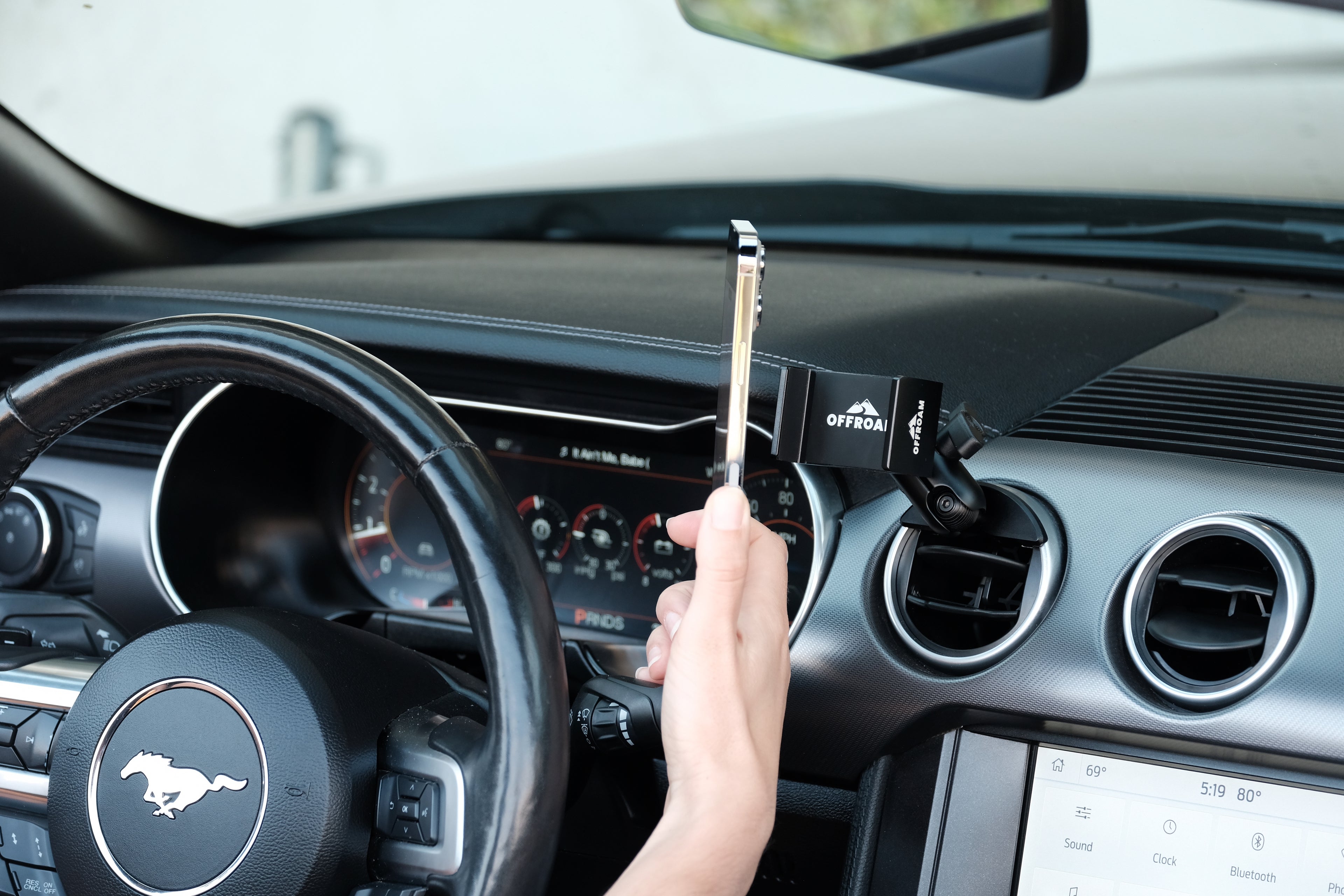 Image of Offroam Phone Mount installed securely in Ford Mustang 2015-2023. This premium phone mount installs easily without drilling or glue. Spring loaded Universal holder for use with any phone. Perfect placement without blocking screens, driver view, or air flow. Fully adjustable positioning.