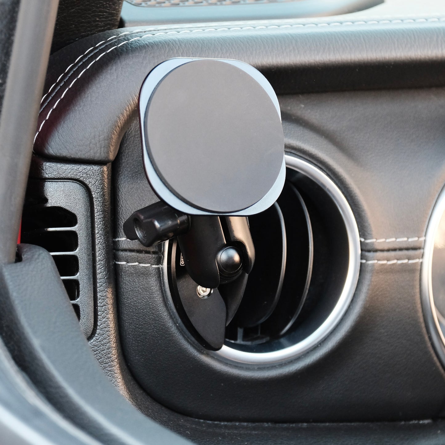 Image of Offroam MagSafe-compatible Phone Mount installed securely in Jeep Wrangler 2018-2023 | Gladiator 2019-2023. This premium phone mount installs easily without drilling or glue on outer vent bezel. High force magnets hold phone on any trail, road, or track. Perfect placement without blocking screens, driver view, or air flow. Fully adjustable positioning.